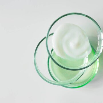 Glass petri dishes with various cosmetic products on white background, copy space. Shampoo, hair conditioner or mask and shower gel, above